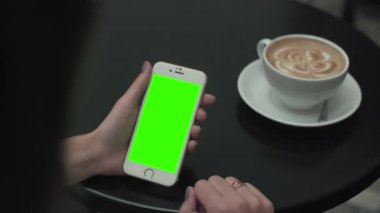 Bir cep telefonu ile yeşil ekran kullanan kadın