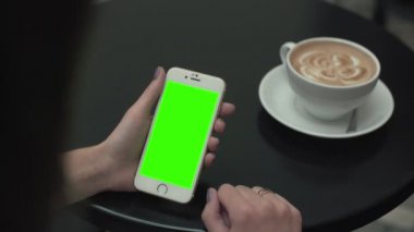 Bir cep telefonu ile yeşil ekran kullanan kadın