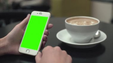 Bir cep telefonu ile yeşil ekran kullanan kadın