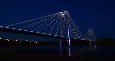 Gece şehrinde nehrin üzerinde parlayan köprü