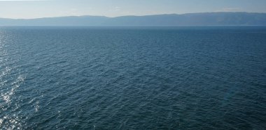 Mavi su göl ve kayaların ufkuna akıyor.