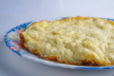 Beyaz arka planda renkli bir tabakta büyük bir omlet.