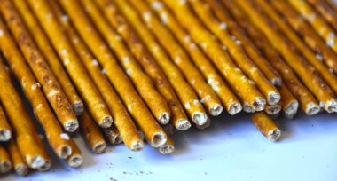 Çıtır tuzlu pipetler, ekmek çubukları. Ev yapımı pişirme. Sarı, bej, kahverengi, uzun, silindir şeklinde ve tarafsız bir arkaplanda..