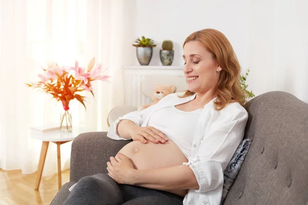 Zwangere vrouw op sofa — Stockfoto