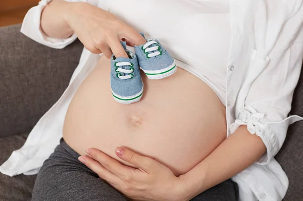 Mulher grávida com sapatos de menino — Fotografia de Stock