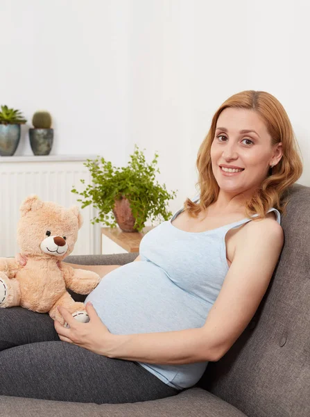 Zwangere vrouw met een teddybeer — Stockfoto