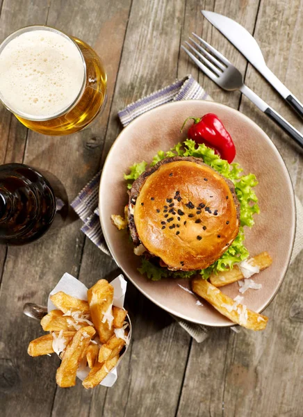 Burger, fries and beer on wood