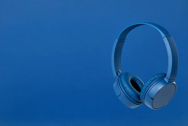 Niebieskie słuchawki bezprzewodowe na niebieskim tle — Zdjęcie stockowe
