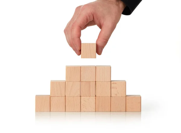Businessman making a wooden cubes pyramid — Stock Image Businessman making a wooden cubes pyramid Stock Photo