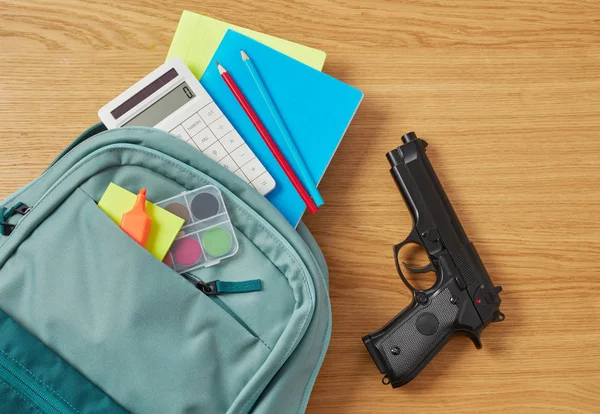Ryggsäck, skolmateriel och pistol — Stockfoto