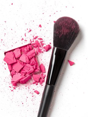 Ezilmiş pembe göz farı ve beyaz arka planda makyaj fırçası.