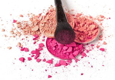 Ezilmiş yüz pudraları ve beyaz arka planda makyaj fırçası.