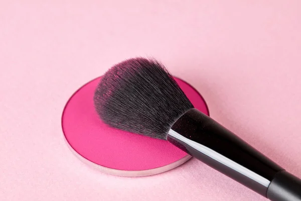 Professional make-up brush and face powder on pink