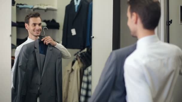 Hombre eligiendo un traje en la tienda de ropa — Vídeo de stock