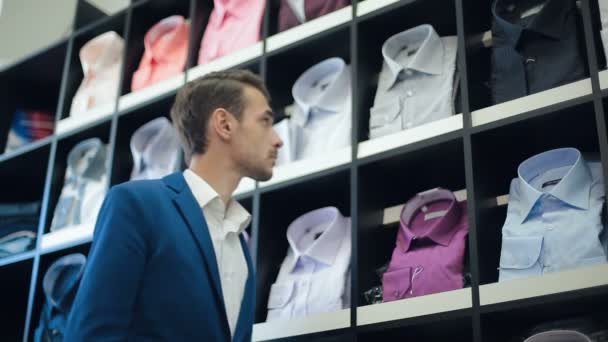 El hombre elige una camisa en la tienda — Vídeo de stock