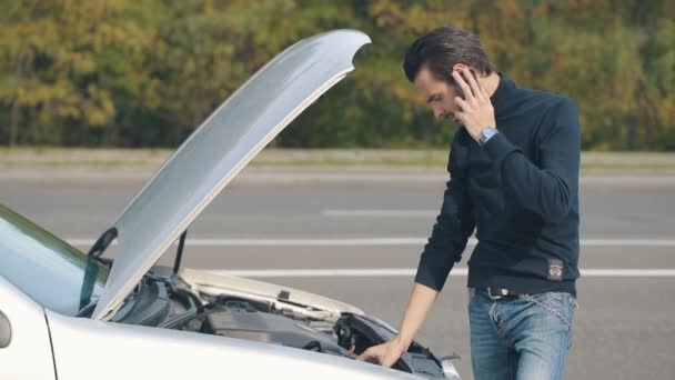 Hombre hablando en un teléfono celular por un coche roto — Vídeos de Stock