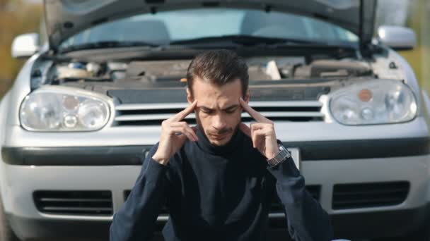 Homem com dor de cabeça na frente de um carro quebrado — Vídeo de Stock