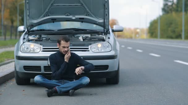 Man sitting in a front of broken with cell phone — Stock Video