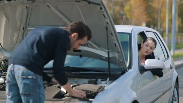 Мужчина ремонтирует сломанную машину для женщины — стоковое видео