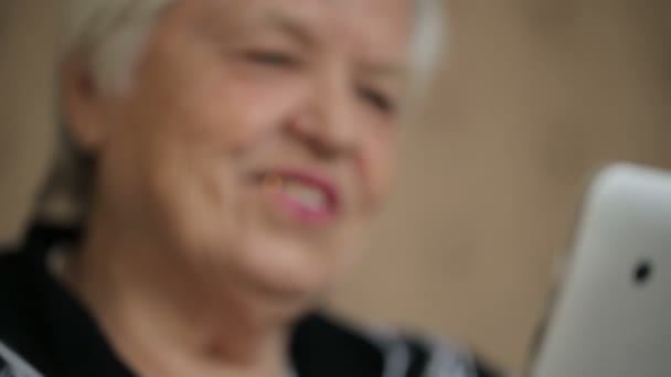 Улыбающаяся пожилая женщина использует планшетный компьютер — стоковое видео