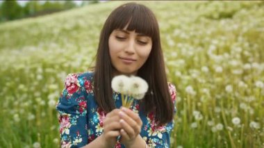 Bir karahindiba gülümseyen kadın üfle