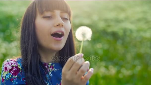 Mujer soplando en un diente de león al atardecer — Vídeo de stock