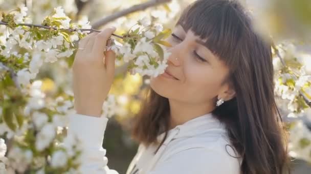 Женщина, нюхающая белые цветы весной — стоковое видео