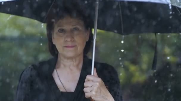 Жінка в чорному одязі під парасолькою під дощем — стокове відео