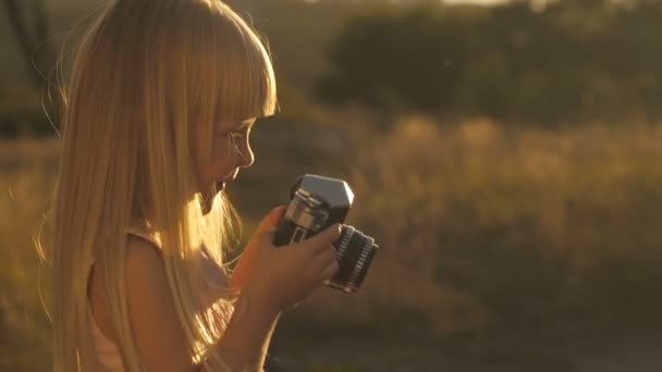 Liten flicka med kamera vid solnedgången — Stockvideo