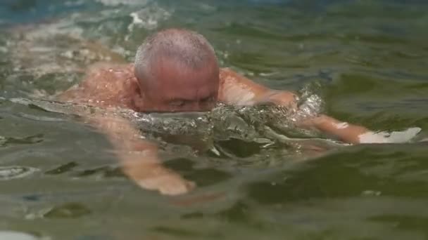 Пожилой человек плавает в бассейне — стоковое видео