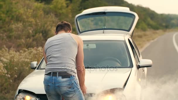 A man looks at a smoking engine of a broken car — Stock Video