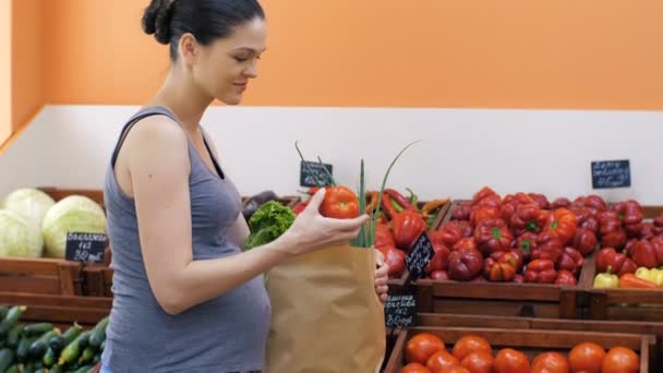 Беременная женщина покупает овощи — стоковое видео