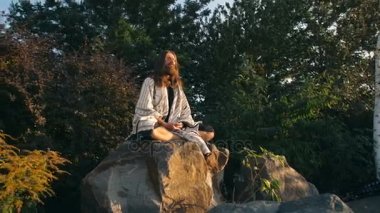 Yogi kayanın üzerinde oturmuş meditasyon yapıyor.