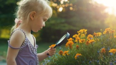 Kız çiçek keşfetmek büyüteç ile