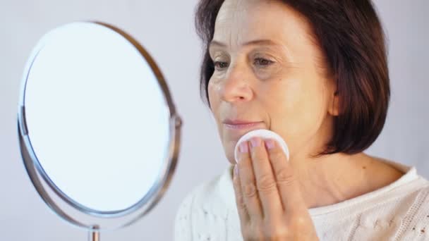 Mujer envejecida limpia la cara con un algodón — Vídeo de stock