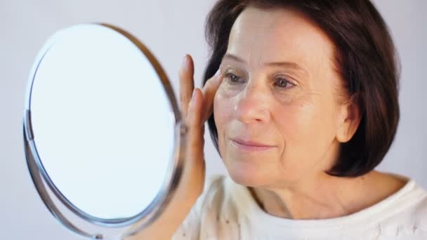 Ältere Frau streicht über die Haut im Gesicht — Stockvideo