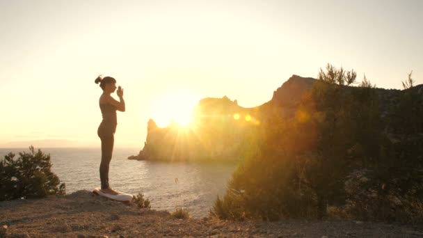 Kvinna gör yoga vid solnedgången nära havet — Stockvideo