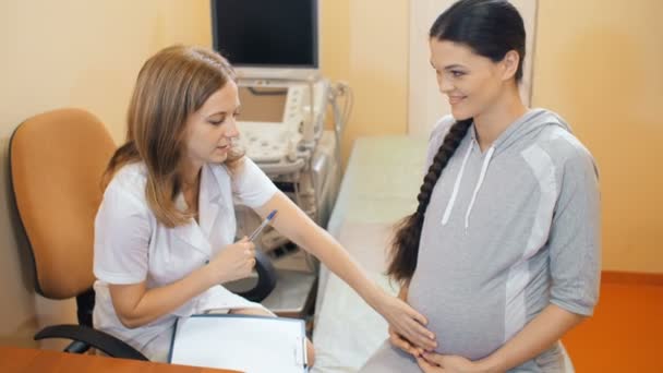 Médico consultando a una mujer embarazada — Vídeos de Stock