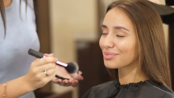 Maquillaje artista hace maquillaje a una chica — Vídeos de Stock