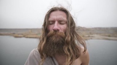 Kapalı gözlü bir adam doğaya meditasyon yapar.