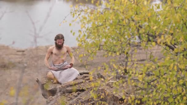 Аскетичный человек занимается йогой на природе — стоковое видео
