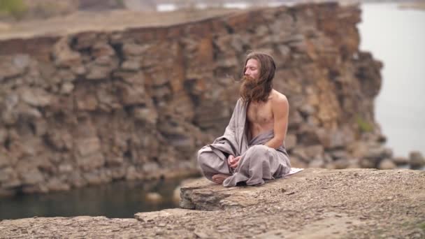 Yogi zittend op de rots bij de zee — Stockvideo