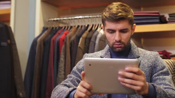 Hombre trabajando en la tableta PC en la tienda de ropa — Vídeos de Stock