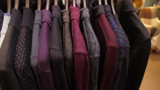 Suéteres en perchas en tienda de ropa — Vídeo de stock