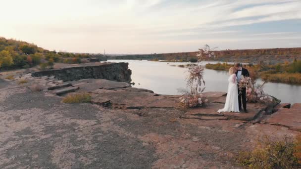 Свадебная пара обнимается на закате — стоковое видео