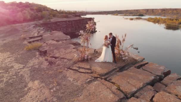 Свадебная пара, стоящая на скале — стоковое видео