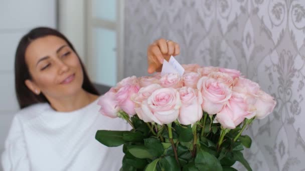 Жінка читає листівку в квітах — стокове відео