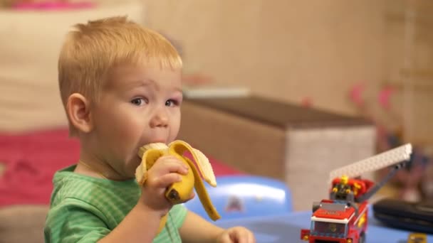 Chico comiendo un plátano en la habitación — Vídeos de Stock