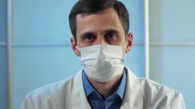 Ofisteki üzgün doktor kameraya bakıyor.