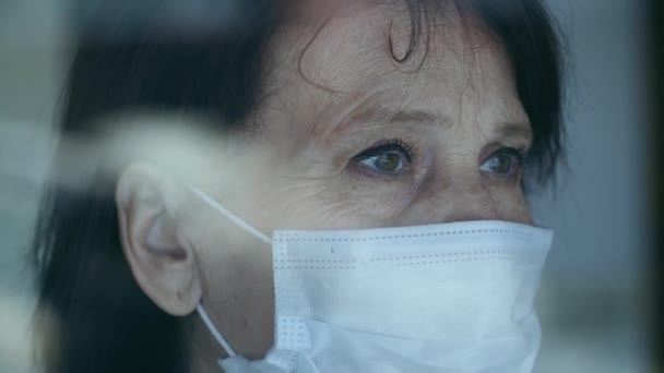 Mujer triste en mascarilla detrás de la ventana — Vídeo de stock